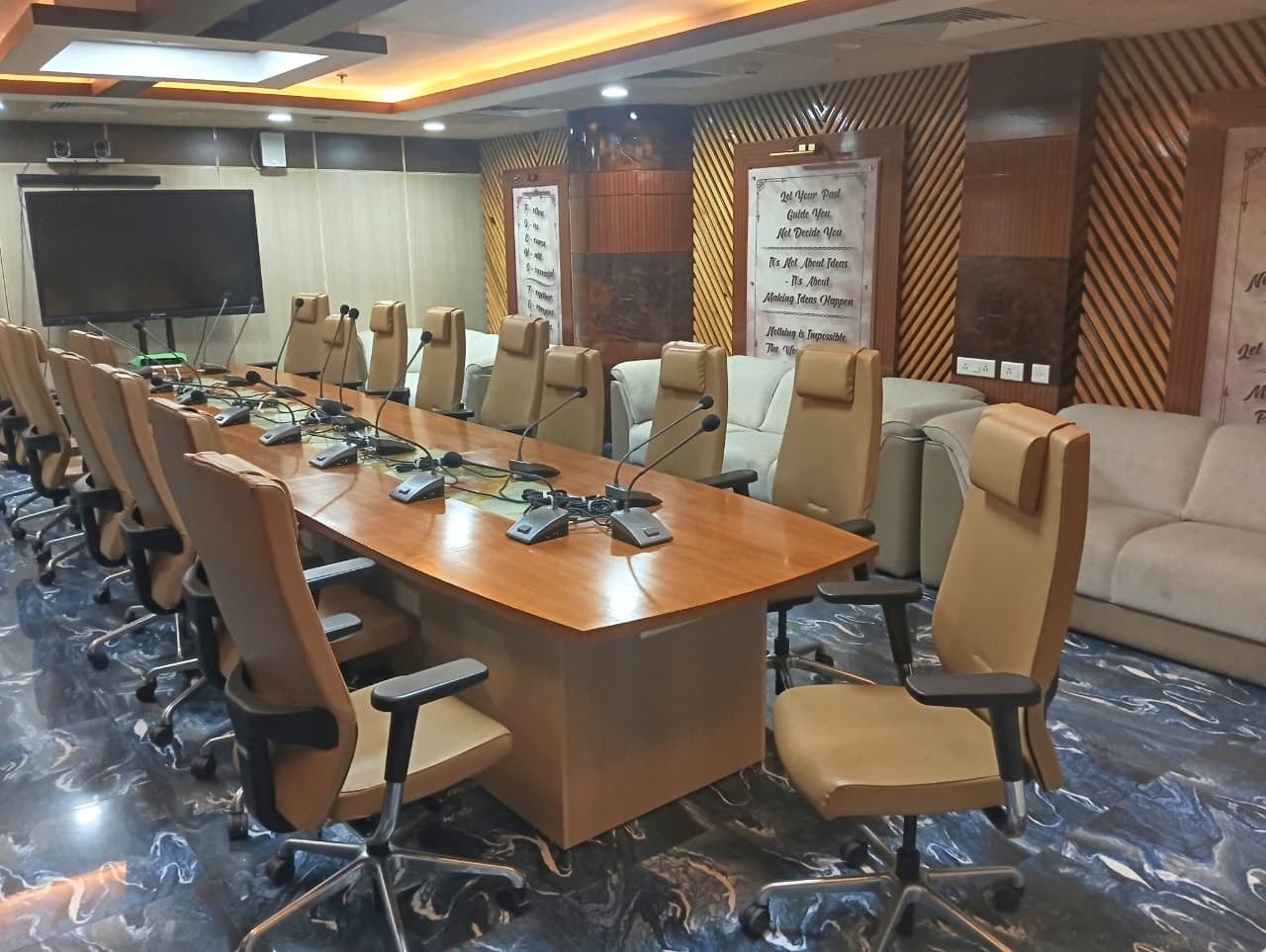 The venue's conference room, set with delegate microphones and facing a wall-mounted display.